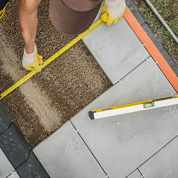 Landscaper measuring a paved patio area during a landscaping project in Sussex